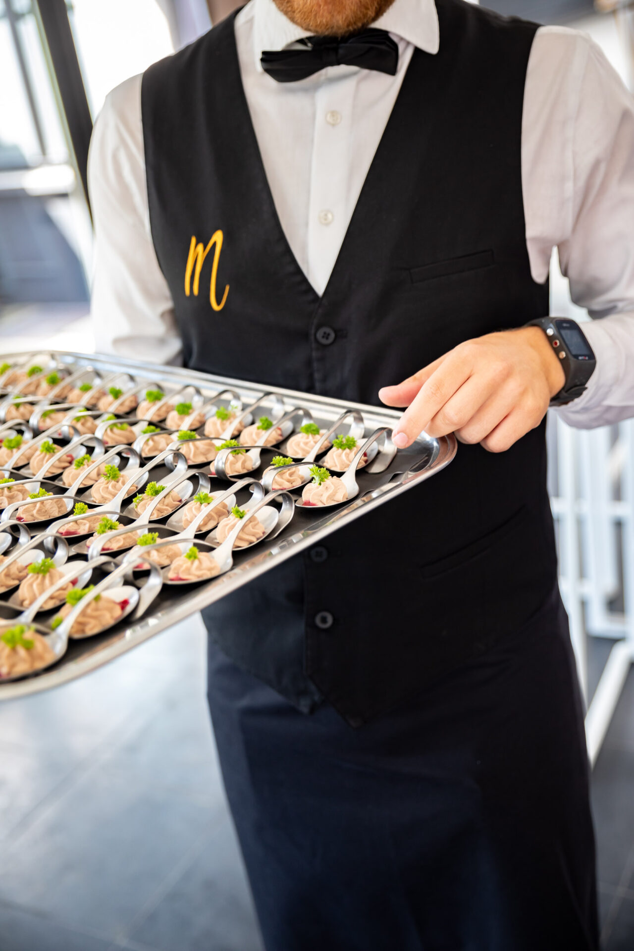 Ober met zeer kleine fingerfood gerechtjes op een schotel